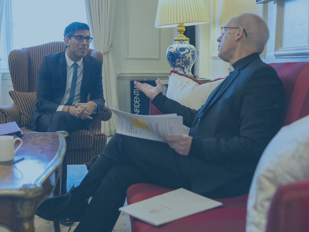 Prime minister Rishi Sunak leans forward out a lounge chair while the Archbishop of Canterbury talks and gestures while sitting on a sofa.