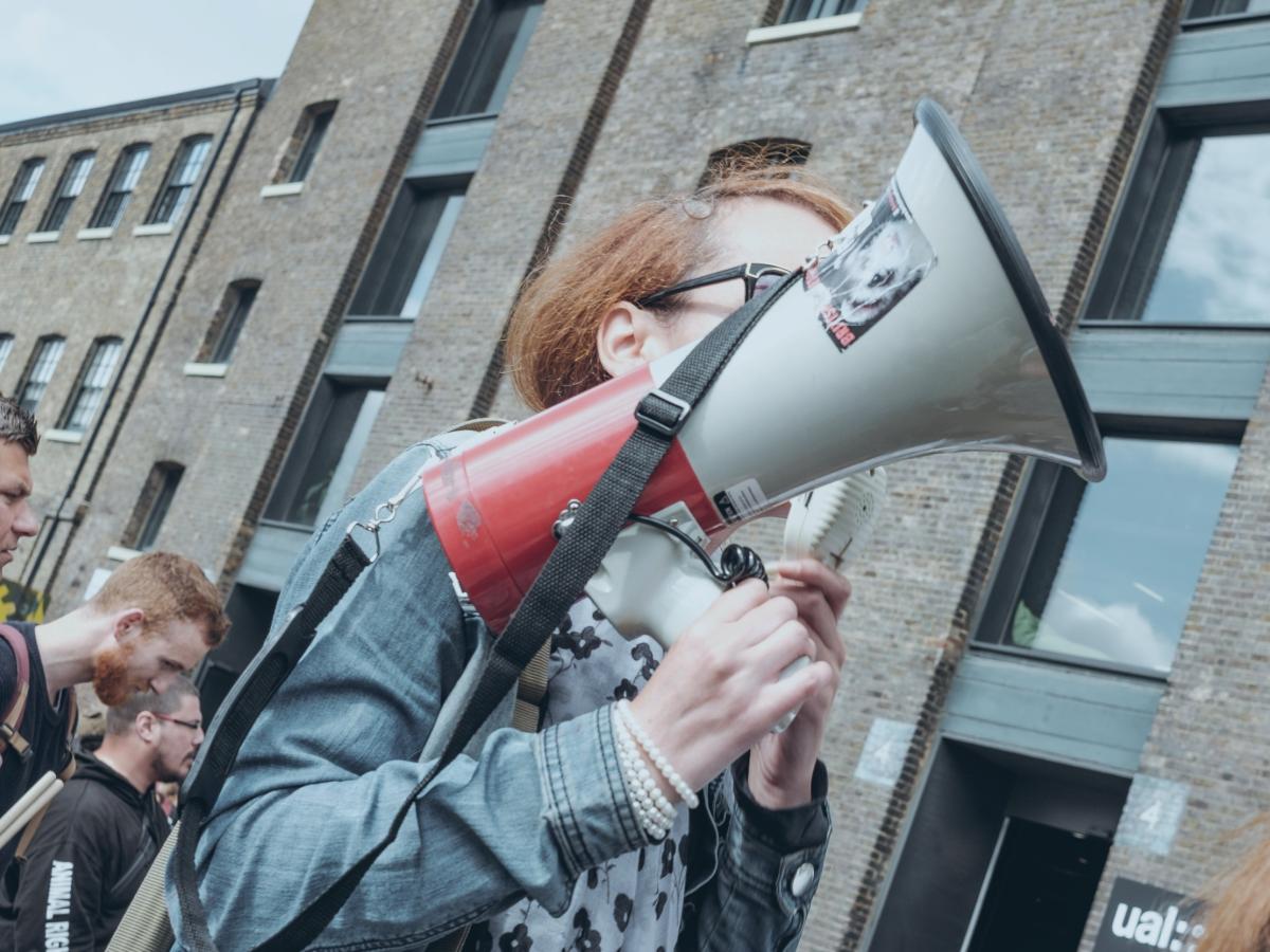 A protestor hold a megaphone up at a demonstration outside a building