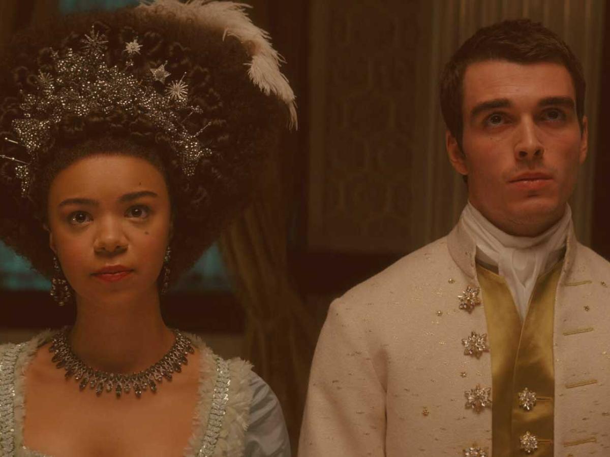 A regency queen and king stand beside each other looking pensive.