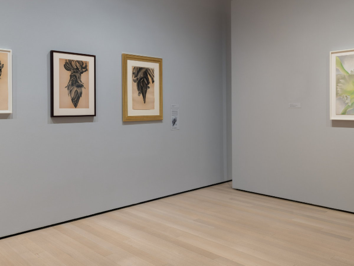 A corner of an art gallery displays three pictures to one side and one to the other.