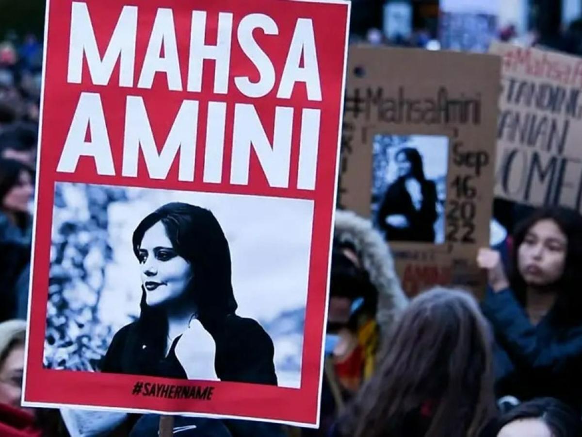 A protester holds a red placard bearing the name and image of Mahsa Amini