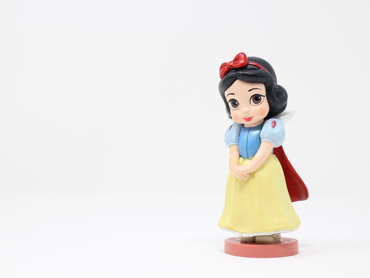 A plastic wind-up Snow White toy stands to the right of the photo, with hands clasped waiting
