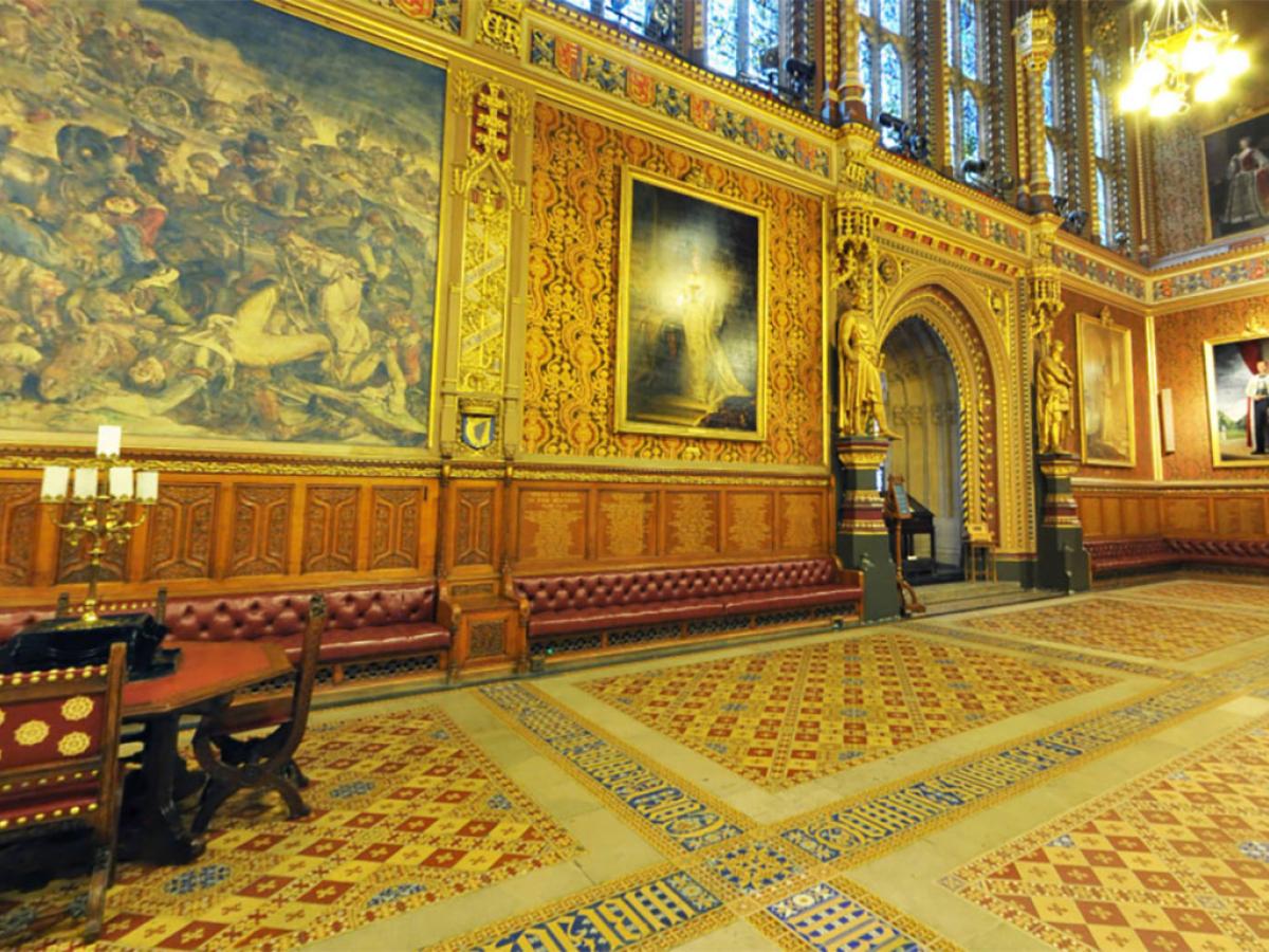A grand highly dercorated hall in the neo-gothic style, with encaustic tiles in the foreground.