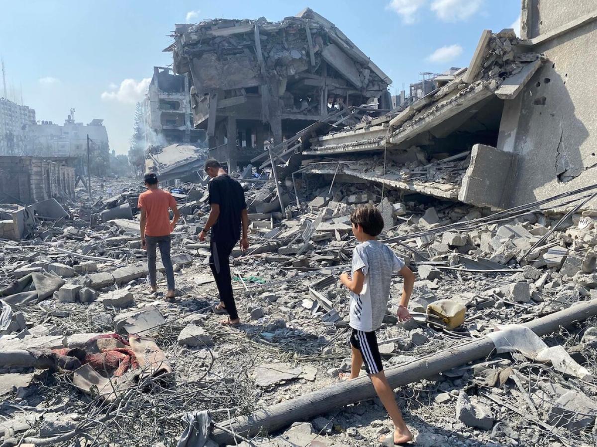 People walk across the rubble beside a recently bombed building.