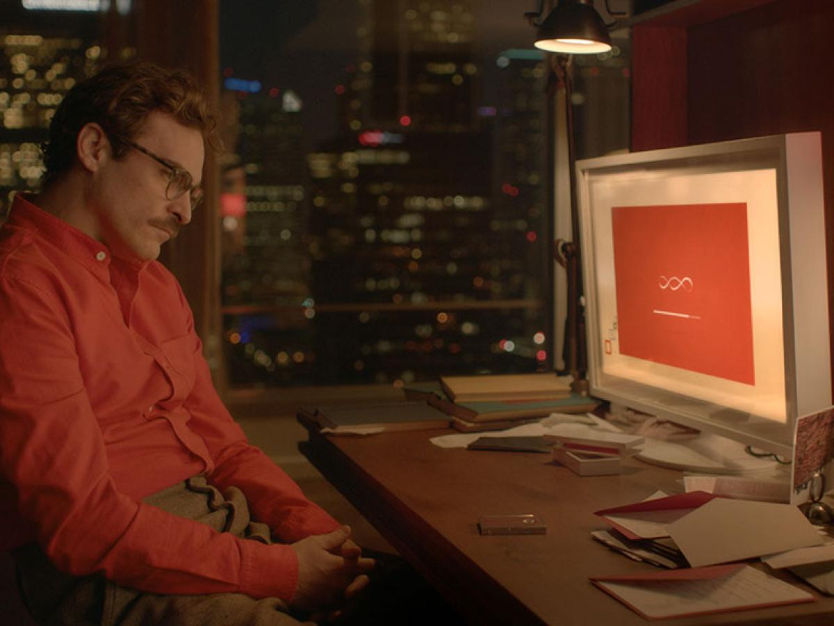 A man in a red shirt slumps in his seat while a computer screen shows a dialogue screen