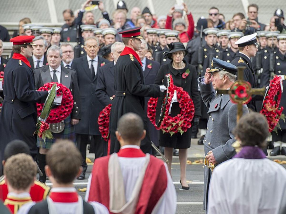 Princes and army officers walk away from a war memorial while others look on.