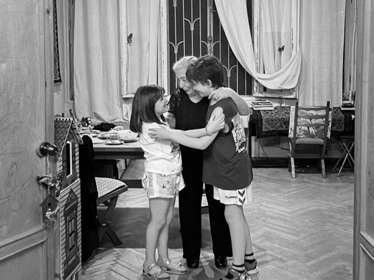 A grandmother is embraced by two grandchildren.