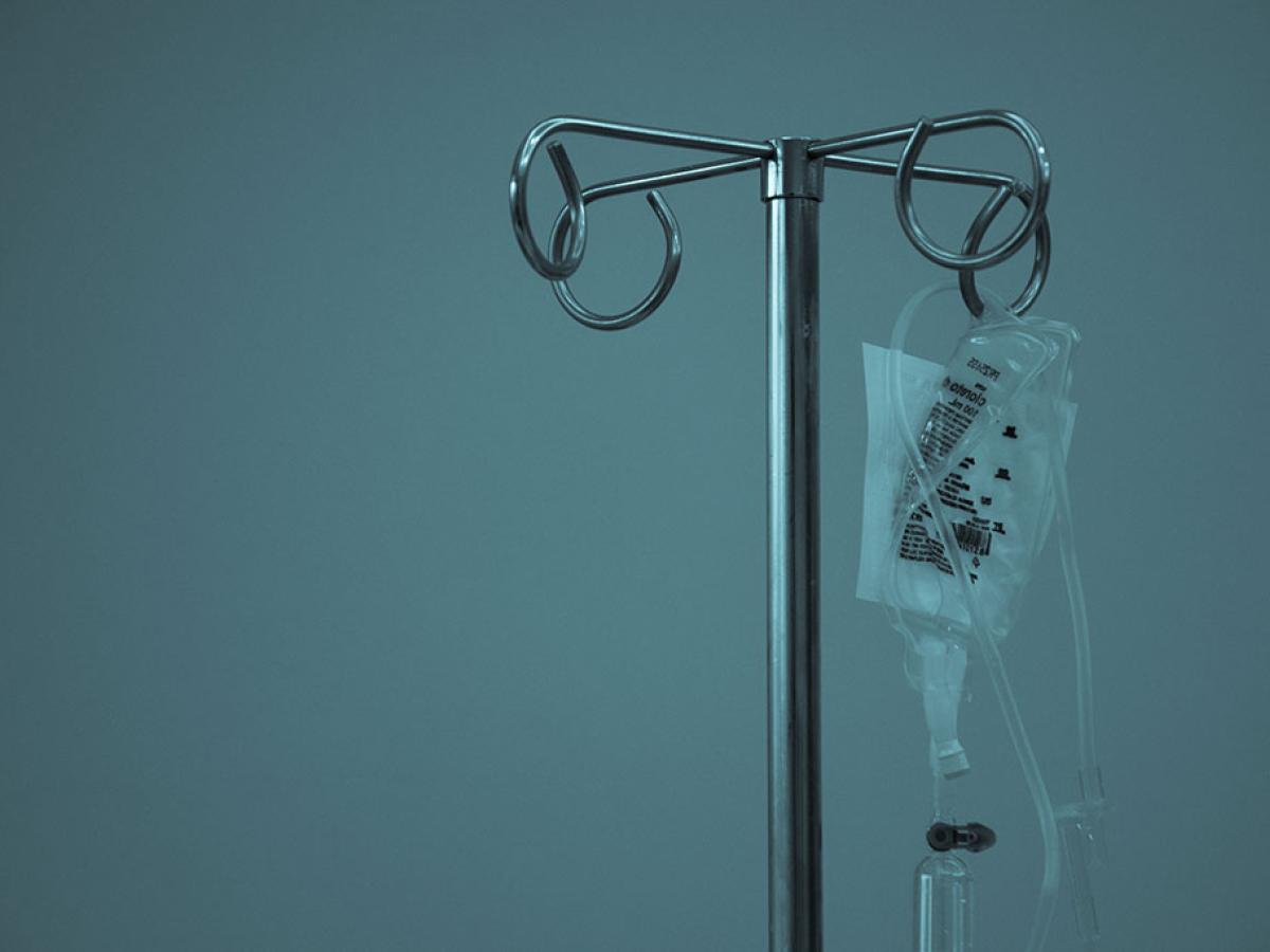 A IV drip bag hangs from a medical stand.