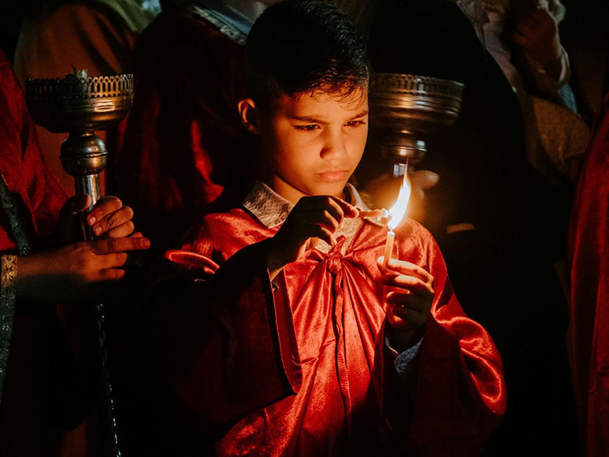 A boy concentrates hard as he holds one candle to another to light it.