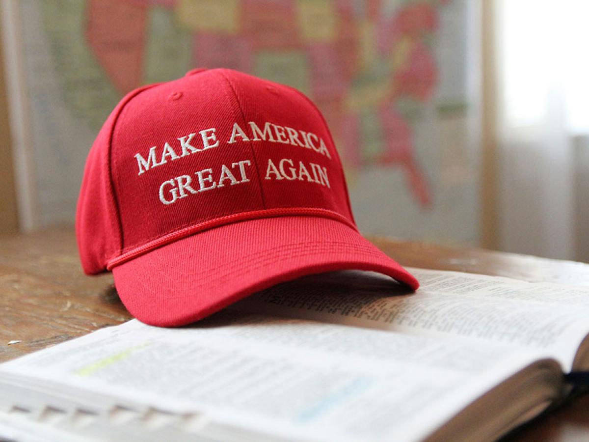 A red baseball cap, with Make America Great Again written across it, sits on an open bible.