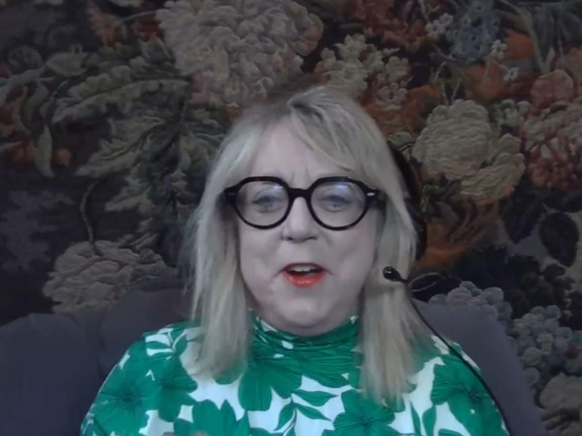 A woman guest on a podcast laughs.