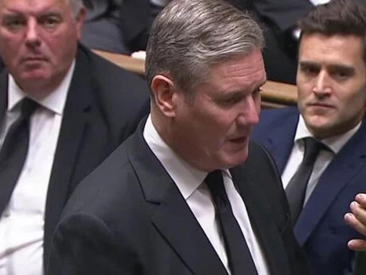 Keir Starmer stands in the House of Commons and recites an oath from a card held up in front of him.