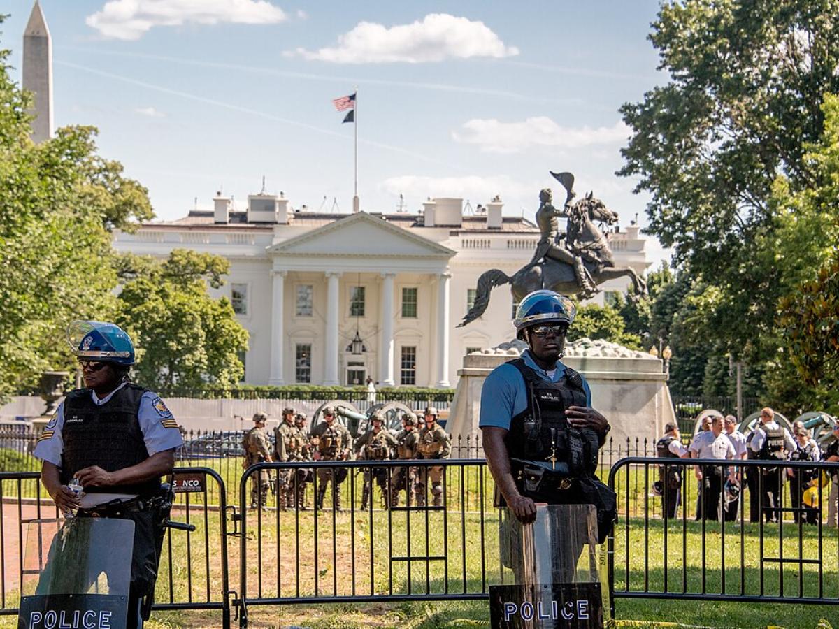 Riot police stand guard outside a White House fence line. 