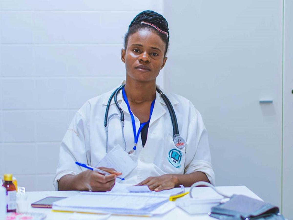 A tired-looking doctor sits at a desk dealing with paperwork.