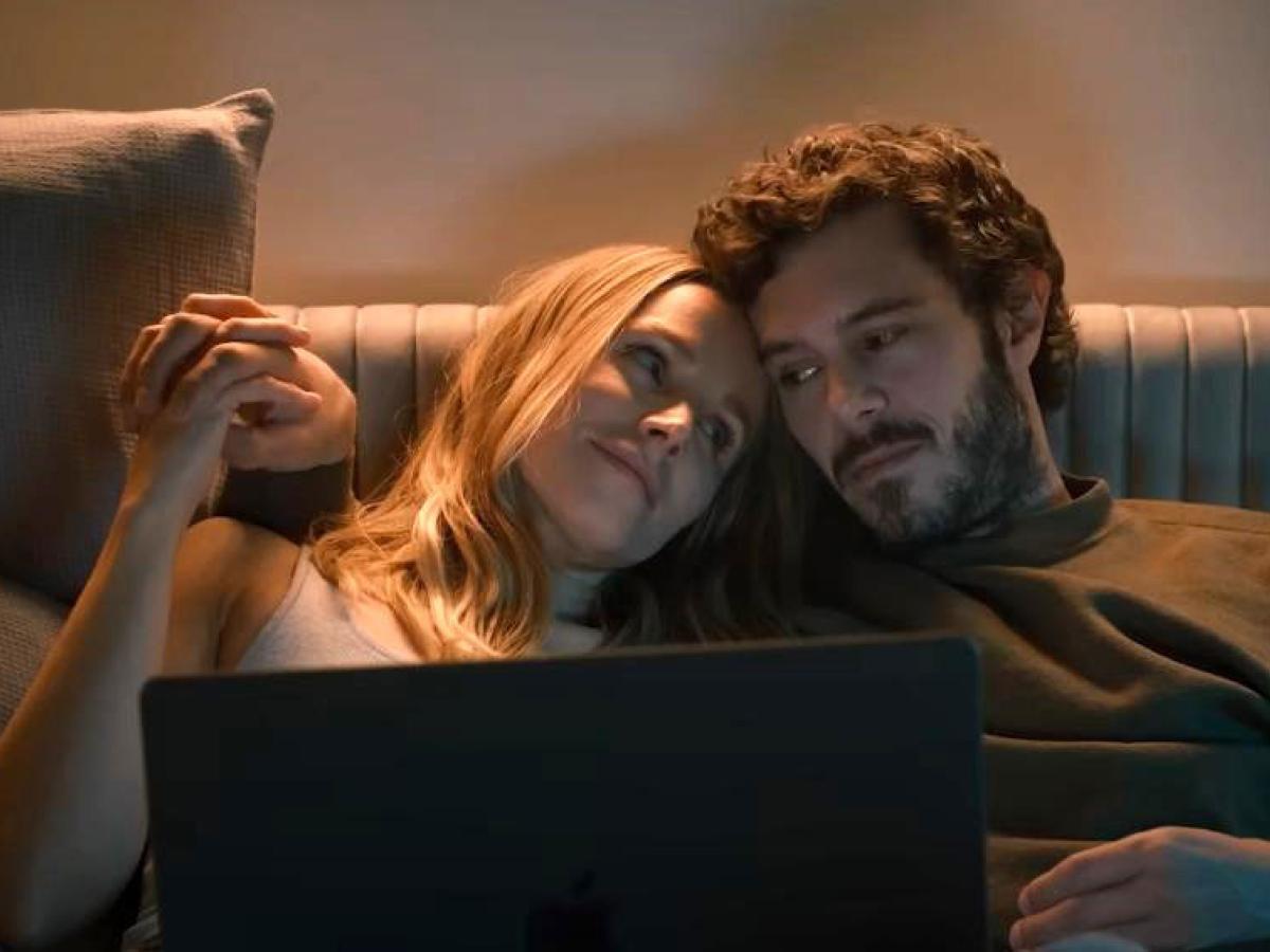 A couple together on a sofa watch a laptop,