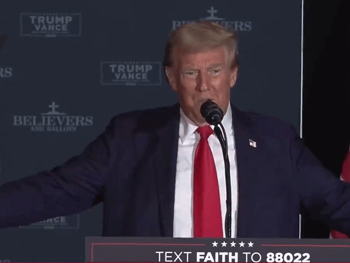 Donald Trump holds his arms out to his side while speaking.