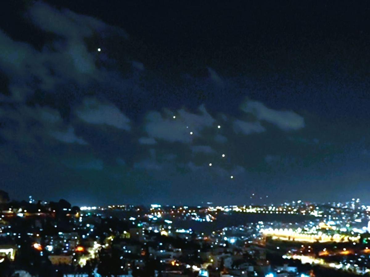 Dots of light, caused by missles, fall across a night sky above the city