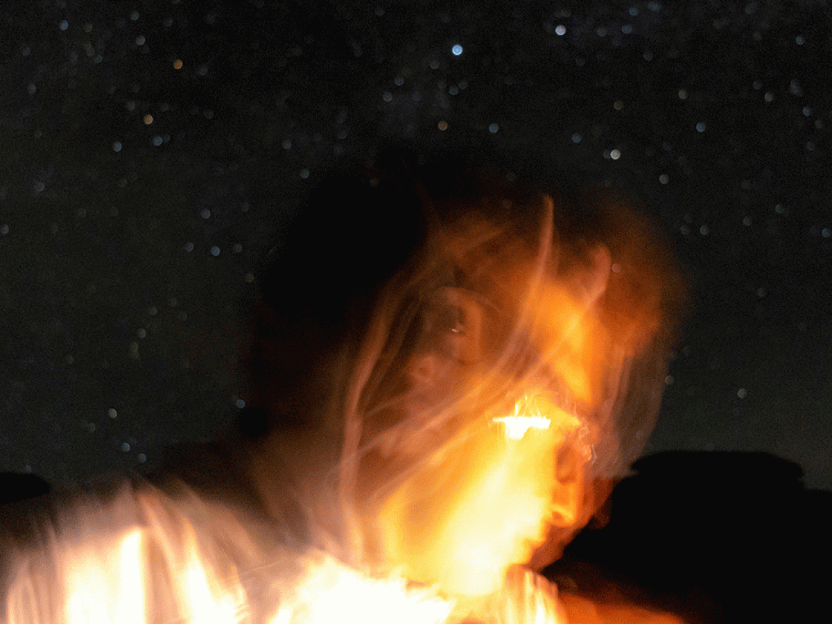 Against a night sky a lit up face is blurred by the camera movement.