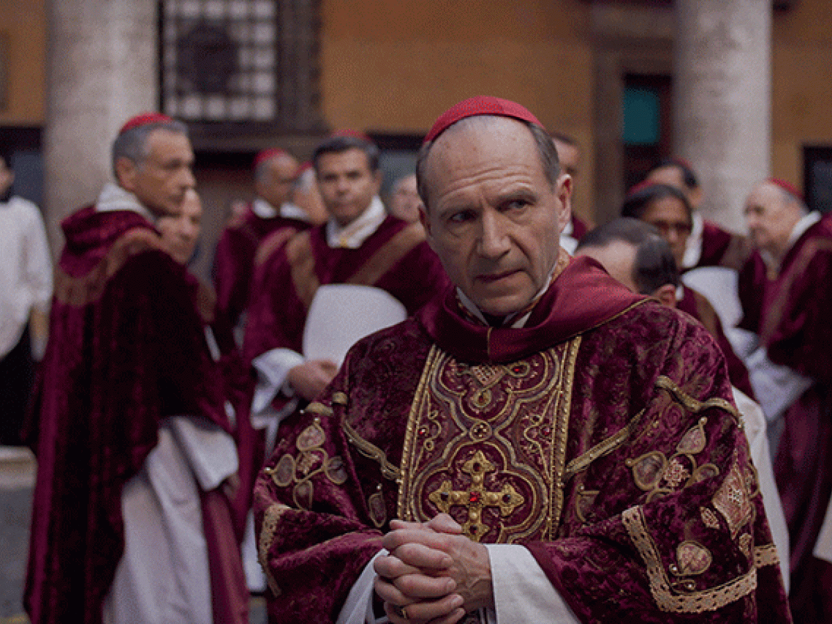 A cardinal glances to the side as he stands amid a gather of clergy,