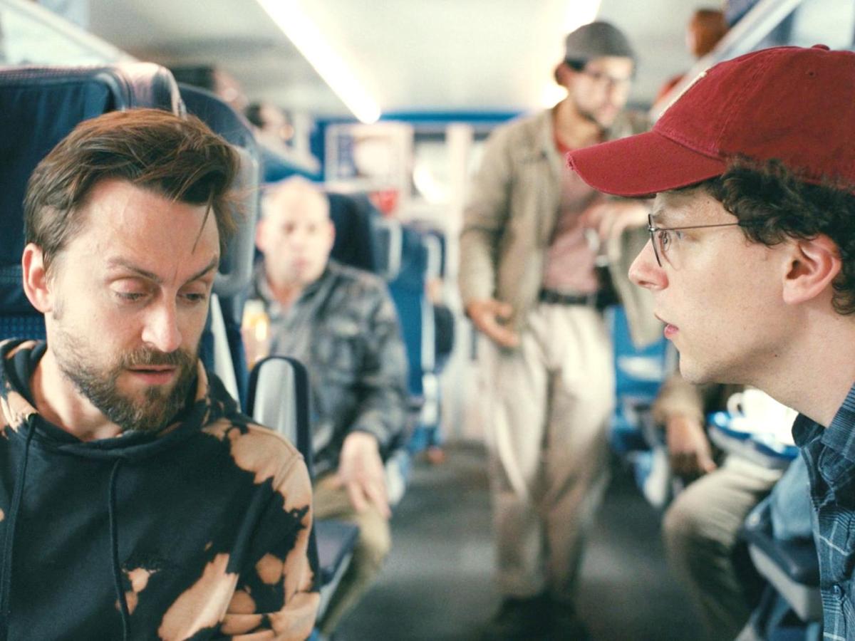 Two male cousins converse across the aisle of a train.