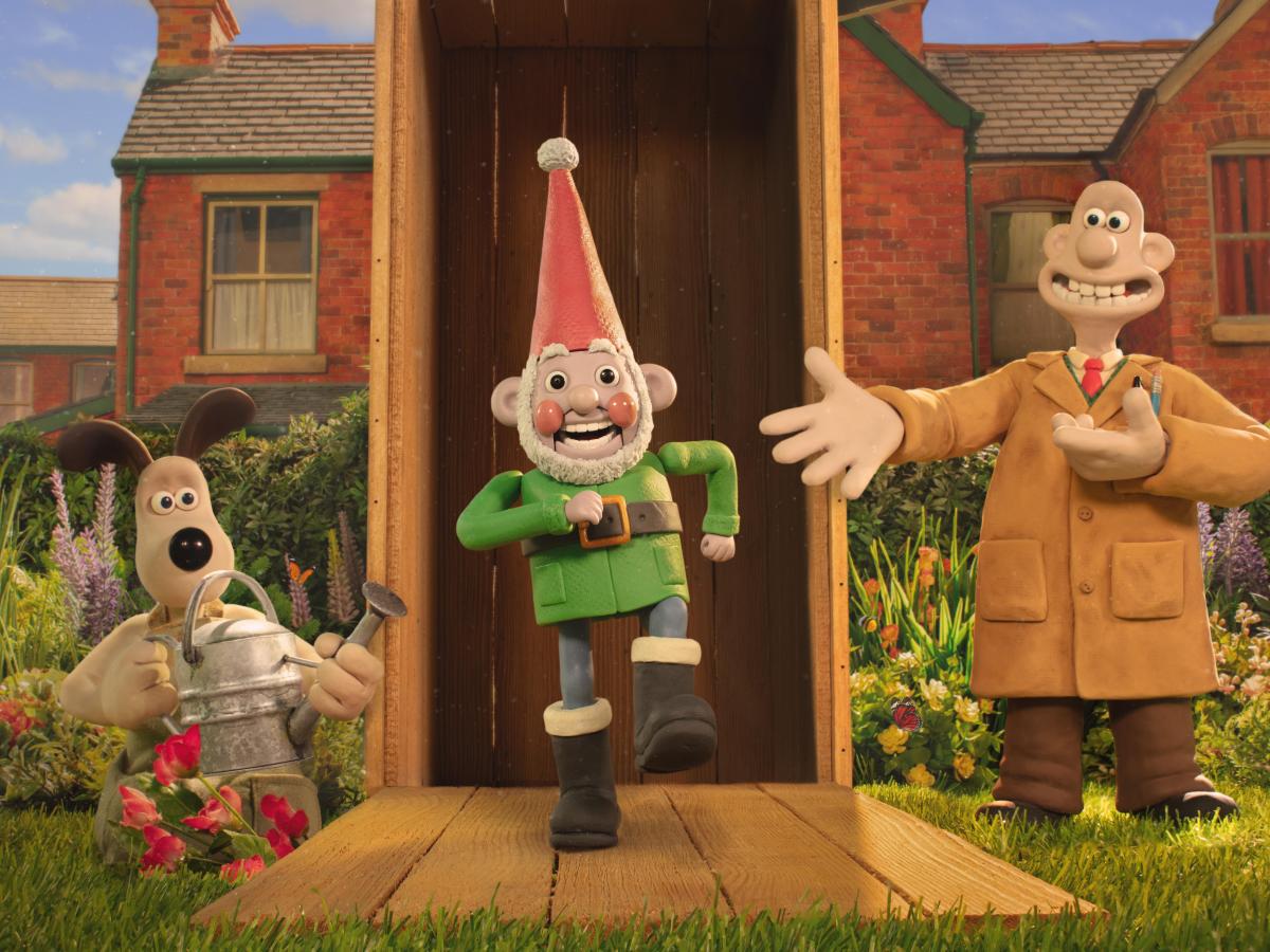 A still from a claymantion film shows three characters, Wallace, Gromit and a robot garden gnome marching out a garden shed.