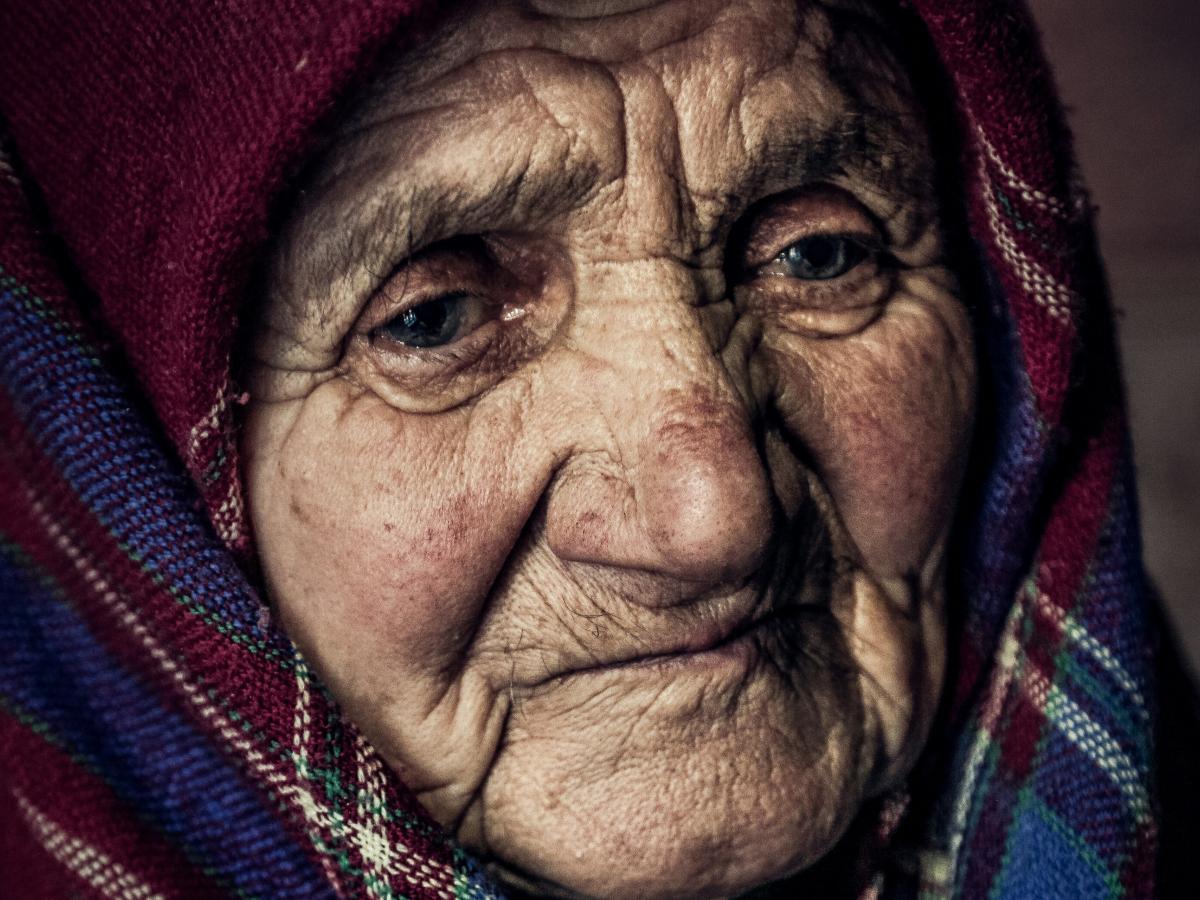 An old woman wearing a shawl looks pensive.