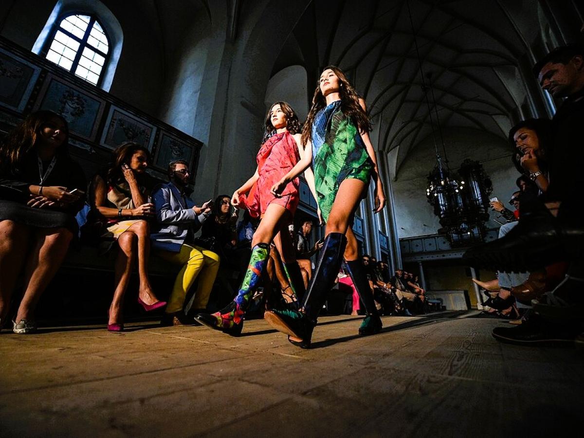 Two models stride along a catwalk of a fashion show held in a church