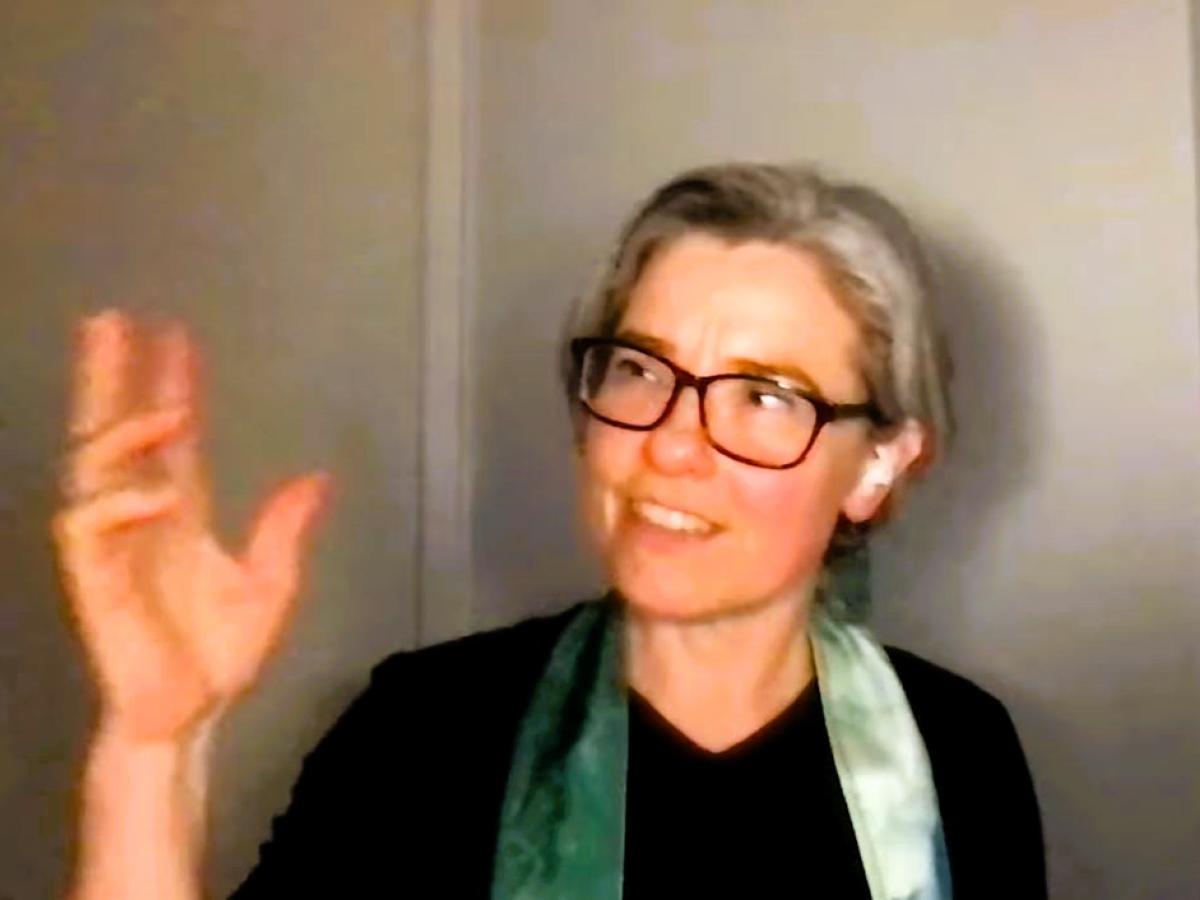 A podcast guest holds up her hand and looks at it while speaking.