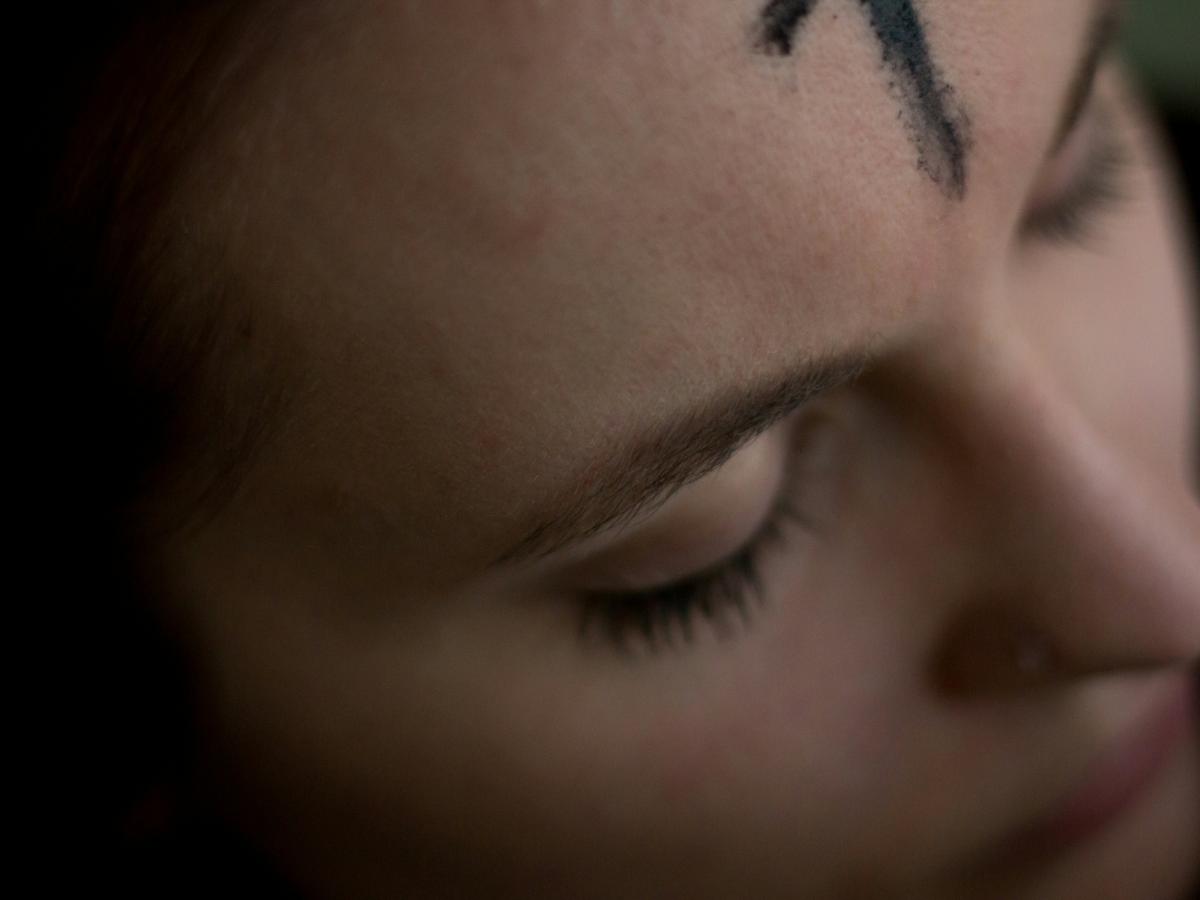 A close up of a forehead bearing an ash cross marked on it.