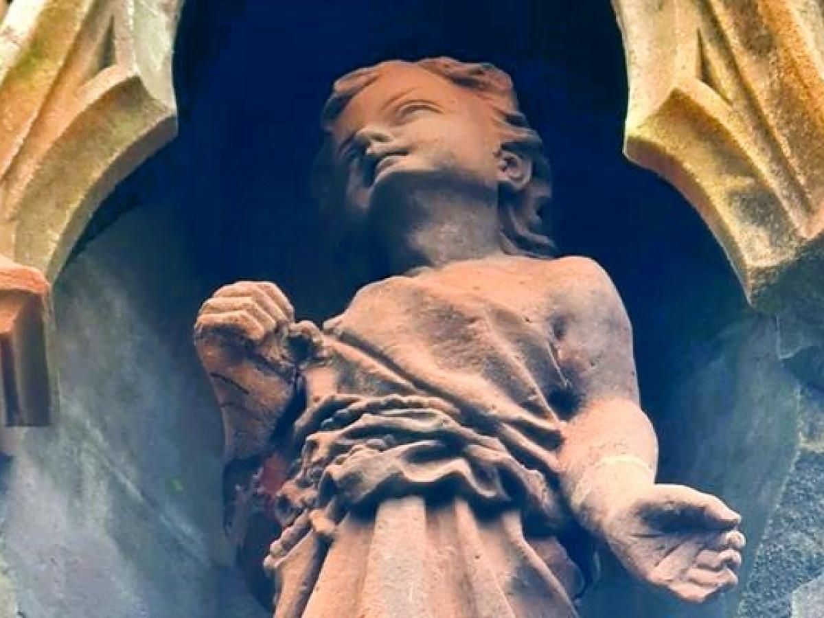 A red sandstone statue of Jesus as a child.