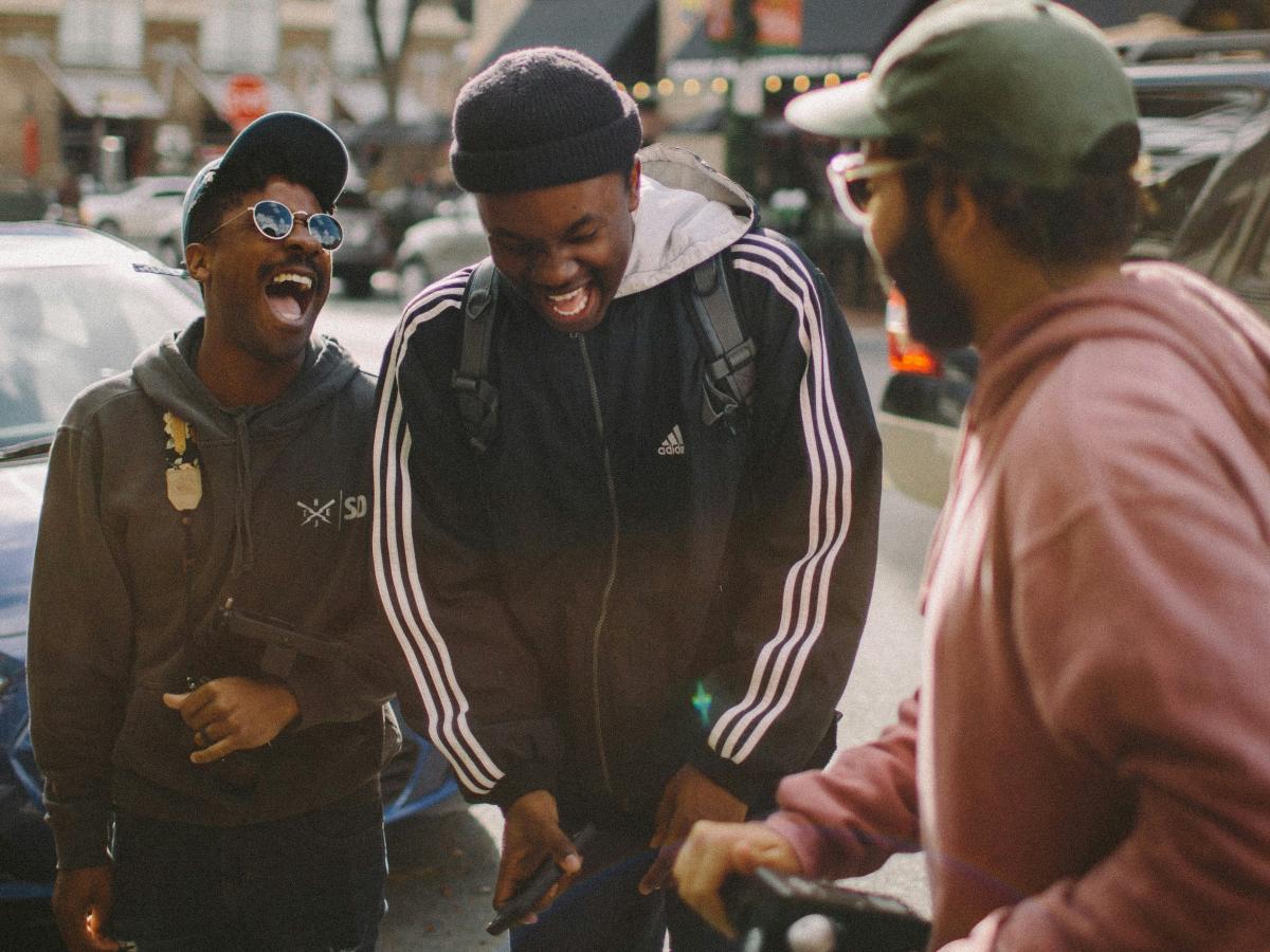 Three friends in the street laugh together.