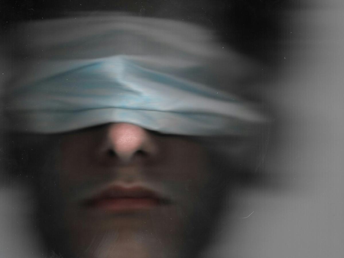 A blurred image of a blindfolded man.