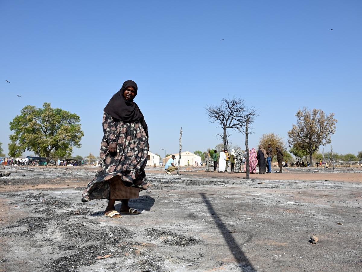 A Sudanese woman walks across the ashes of a burnt out street market.