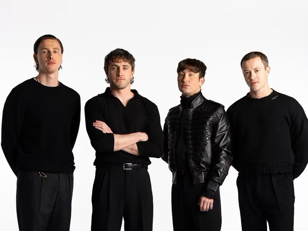 Four actors dressed in black stand together