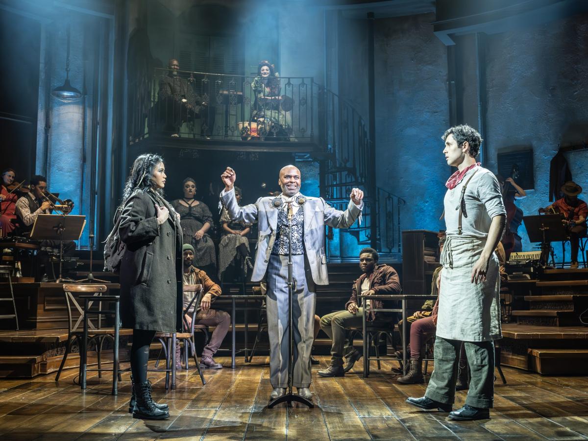 A theatrical staging shows a couple seperated by a man standing between them.