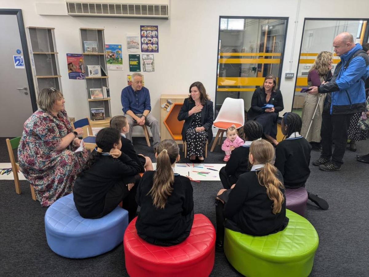 Children sit in a library listening to a story
