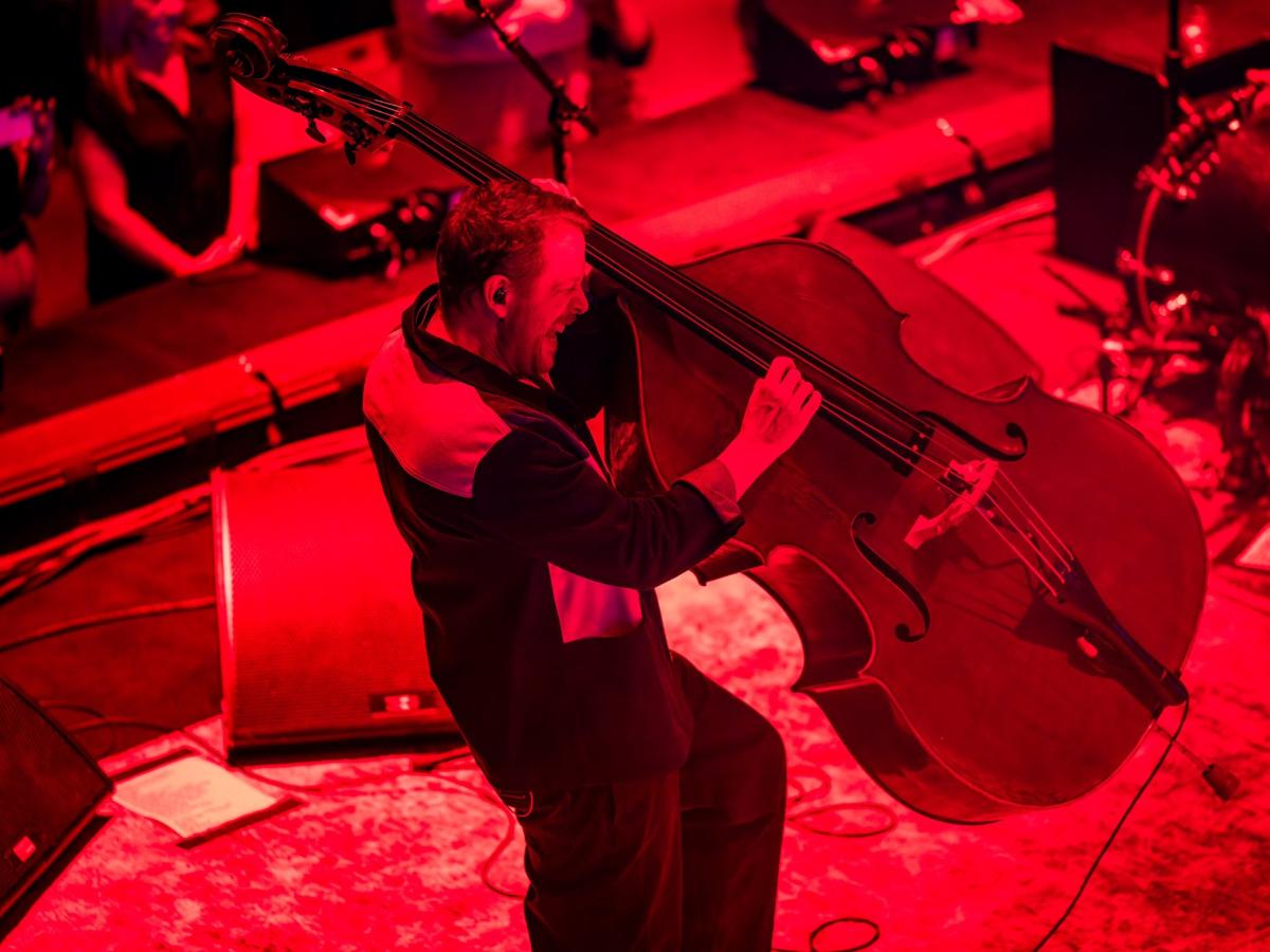 A bassist hauls a double bass of its base as he plays it.