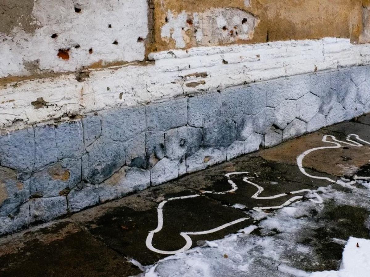 Bullet holes on a wall and white paint outlines mark the site of an execution