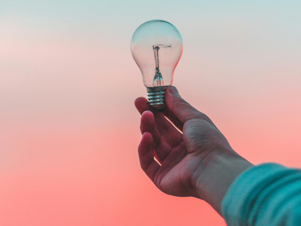 A light bulb is held up against a sunset.