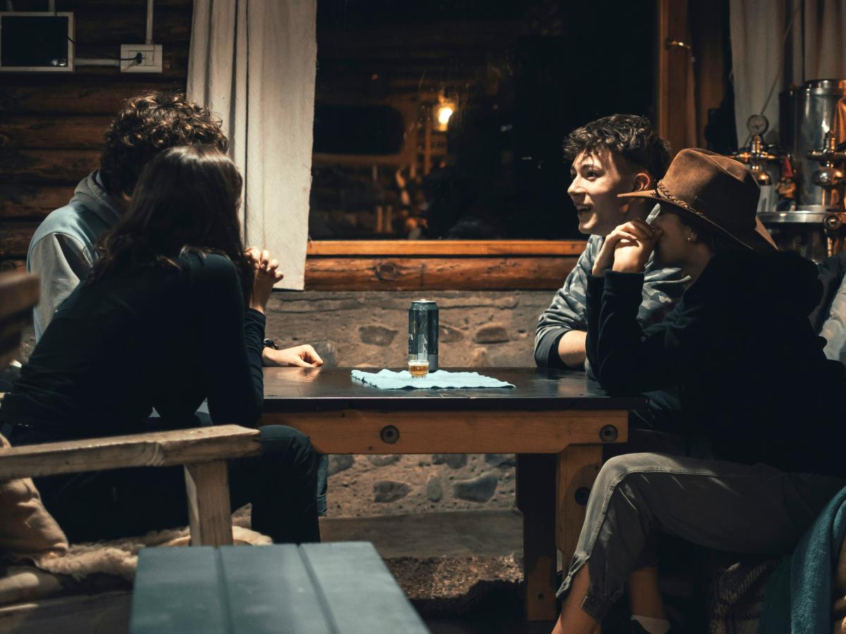 Four people sit round a pub table, some look animated, others pensive.