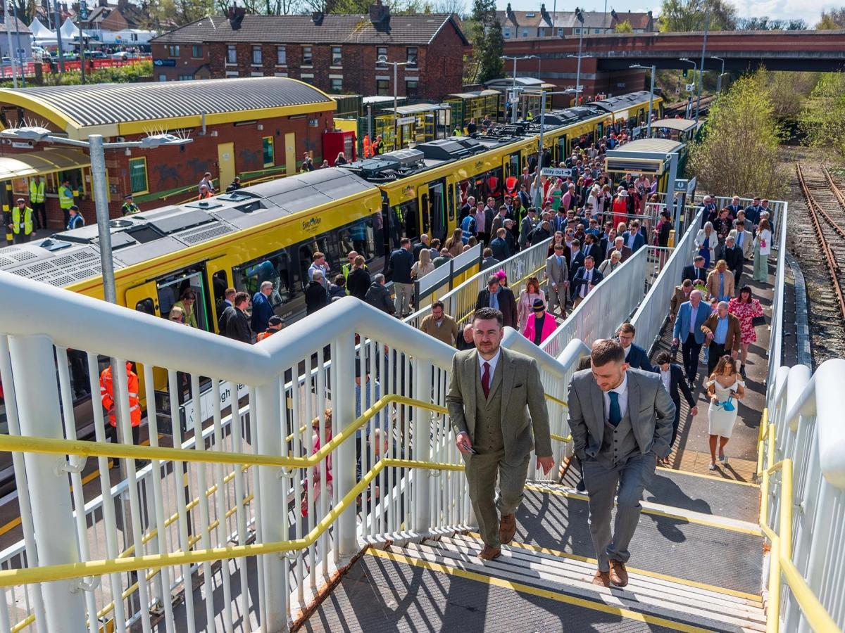Smartly dressed people crowd a station platform and stairs.