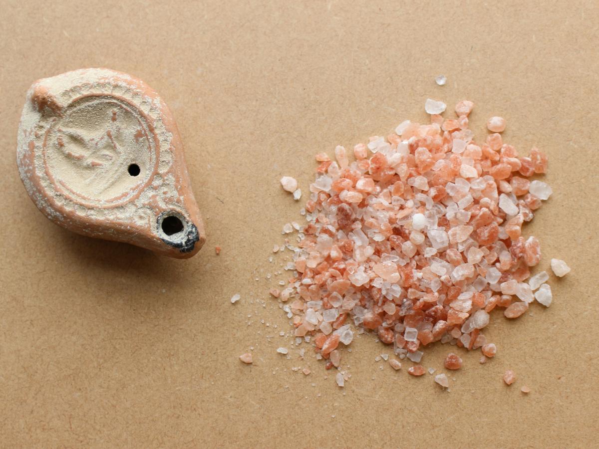 An ancient salt shaker sits next to a pile of crushed rock salt.