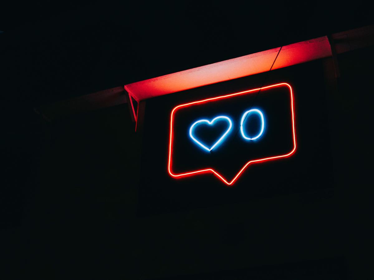 A neon sign depicts a message balloon with a heart symbol and a zero next to it.