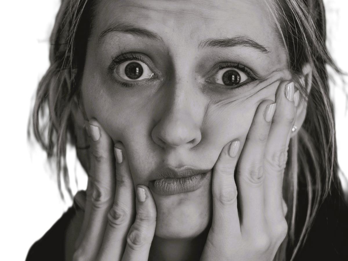 A perplexed looking woman hold her cheeks up with her fingers.