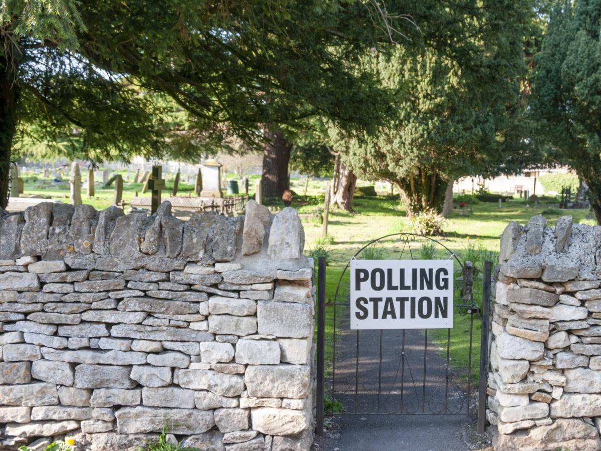 A gate to a churchyard displays a sign saying polling station.