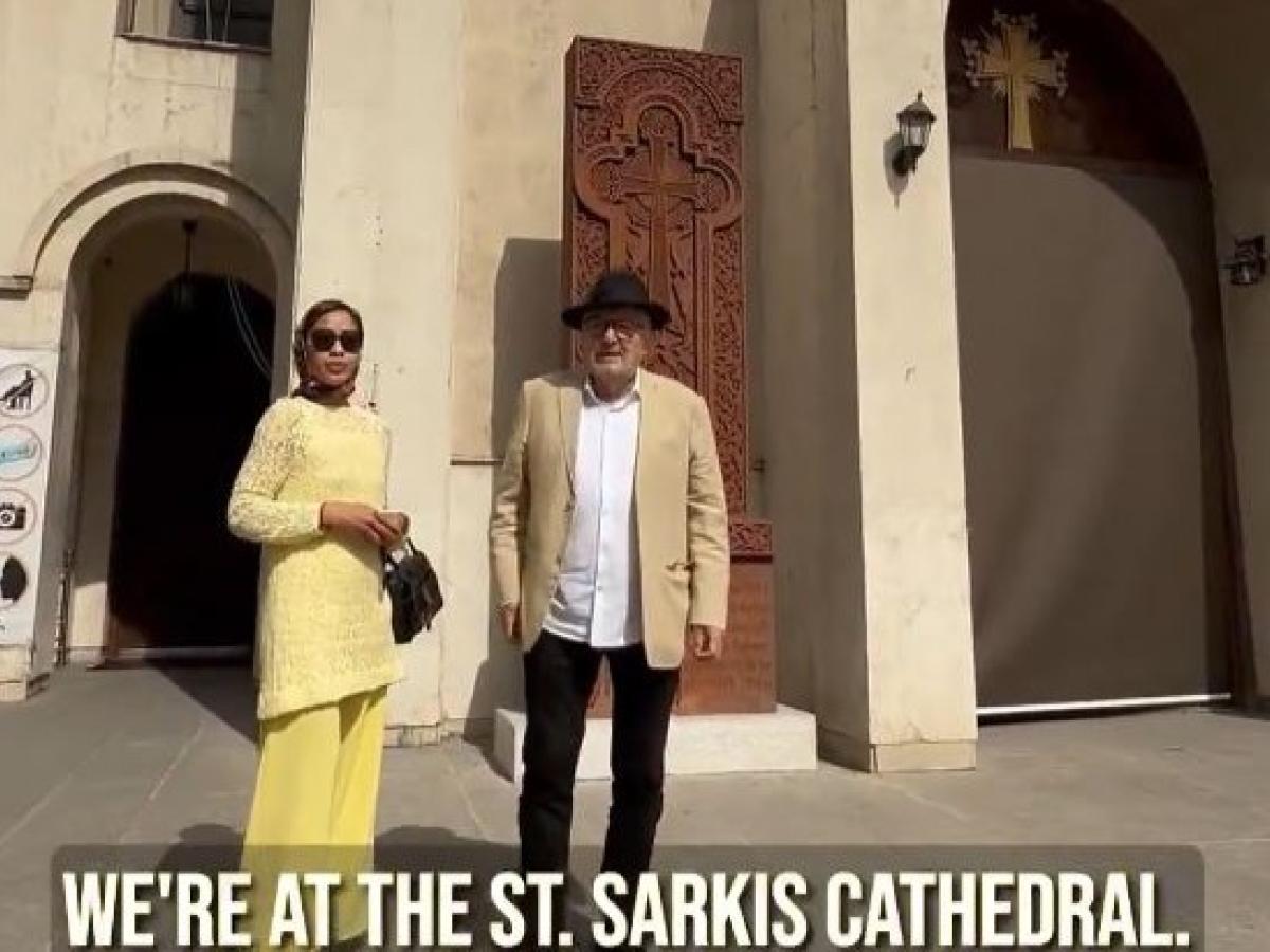 A couple stand on the steps of a cathedral in Iran.