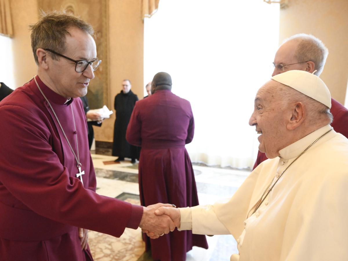 An Anglican bishop wearing purple shakes hands with the Pope.