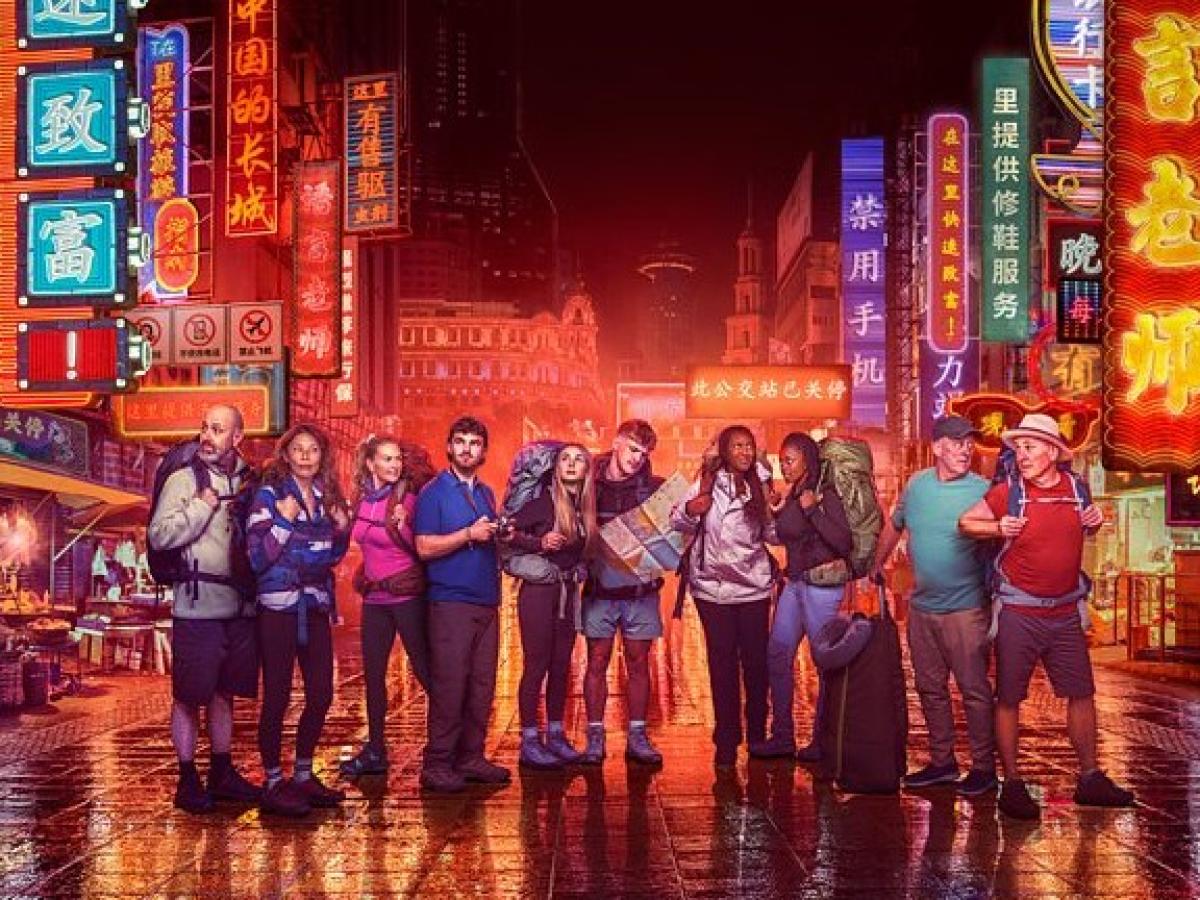 Contestants in Race Across the world stand in front of neon-lit Chinese street scene