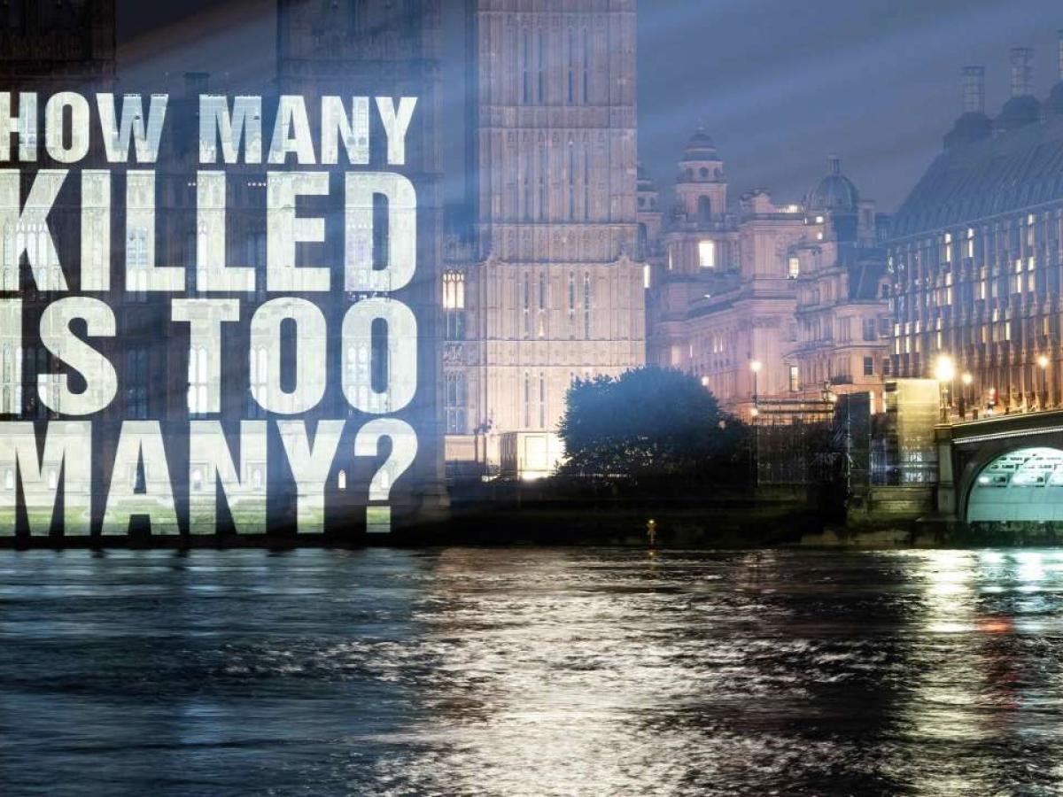 A sign projected on to the Houses of Parliament reads: how many is too many.
