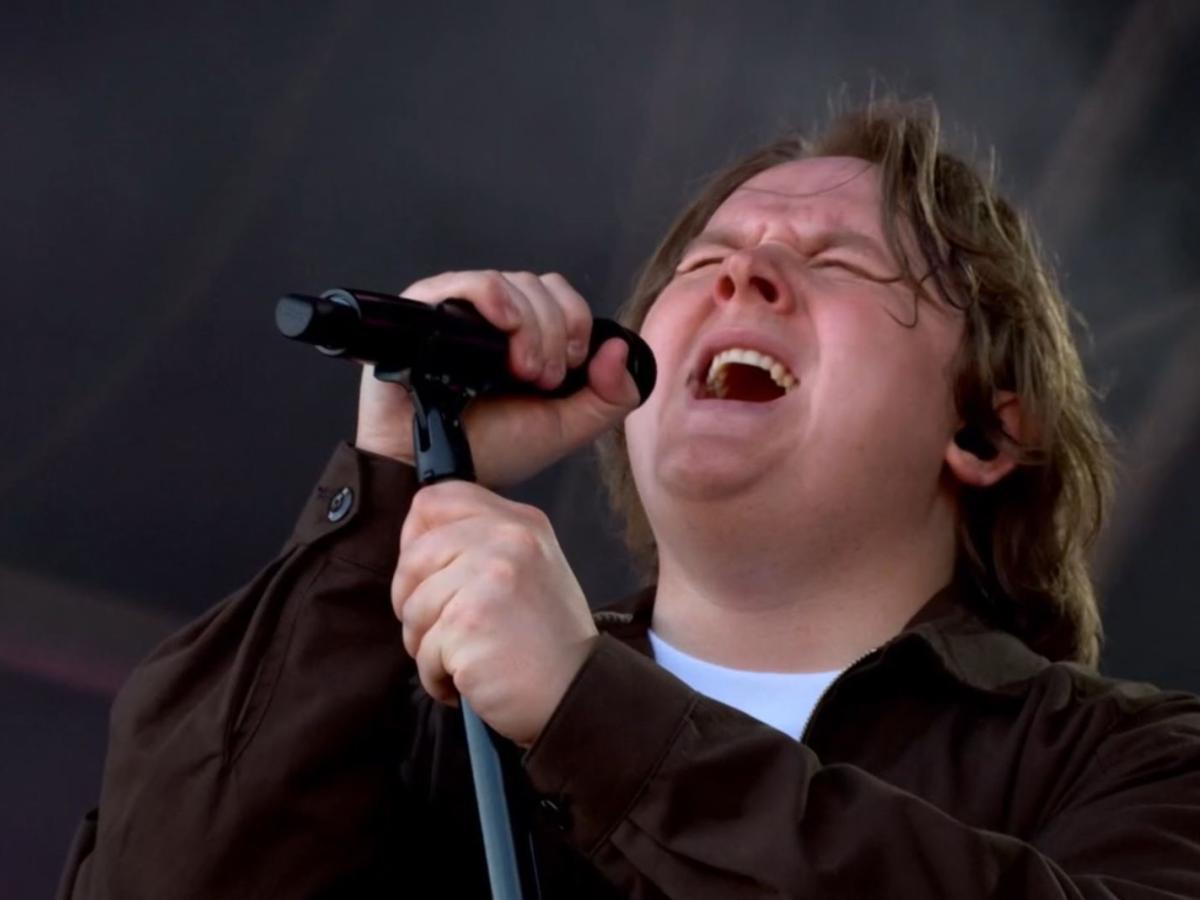 Lewis Capaldi sings with eyes closes, holding a mic and its stand